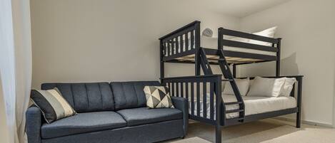 A room with a bunk bed, a sofa, and a carpeted floor.