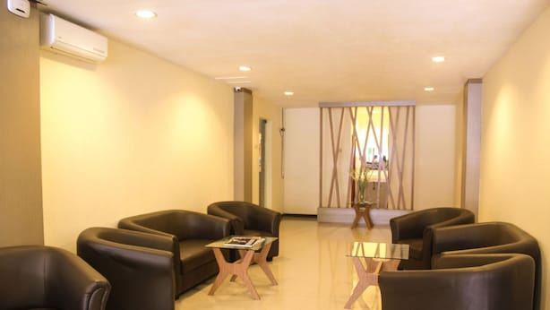 Un espace d’attente moderne, doté de fauteuils en cuir, d’une table basse en verre et d’un mur décoratif.