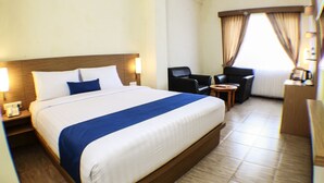 Une chambre d’hôtel avec un grand lit, un bureau, deux chaises et une petite table.