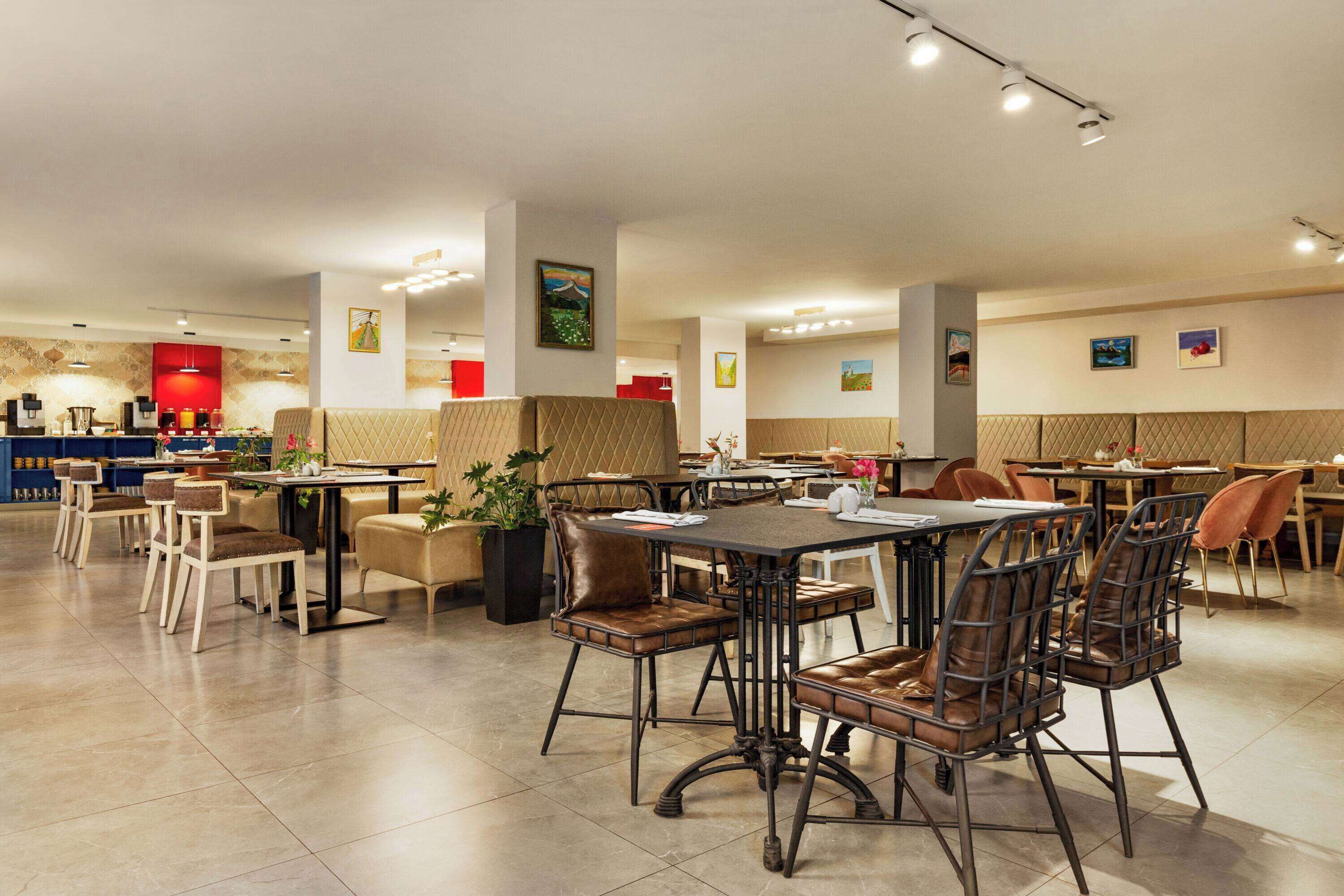 Un restaurante espacioso con varias áreas de comedor, incluyendo cabinas y mesas con sillas.
