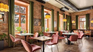 Een restaurant met bakstenen muren, groene gordijnen en moderne meubels. Tafels zijn gedekt met stoelen en middelen.