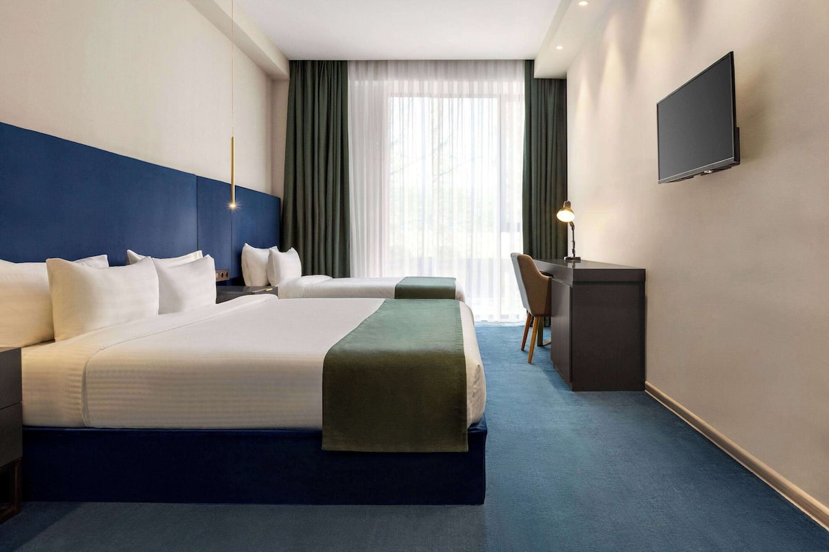A hotel room with a large bed, a desk, and a television on the wall.