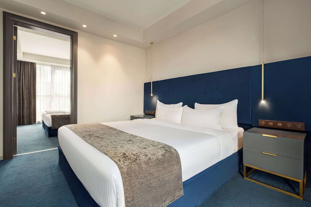 A hotel room with a large bed, a bedside table with drawers, a nightstand, and a mirror.