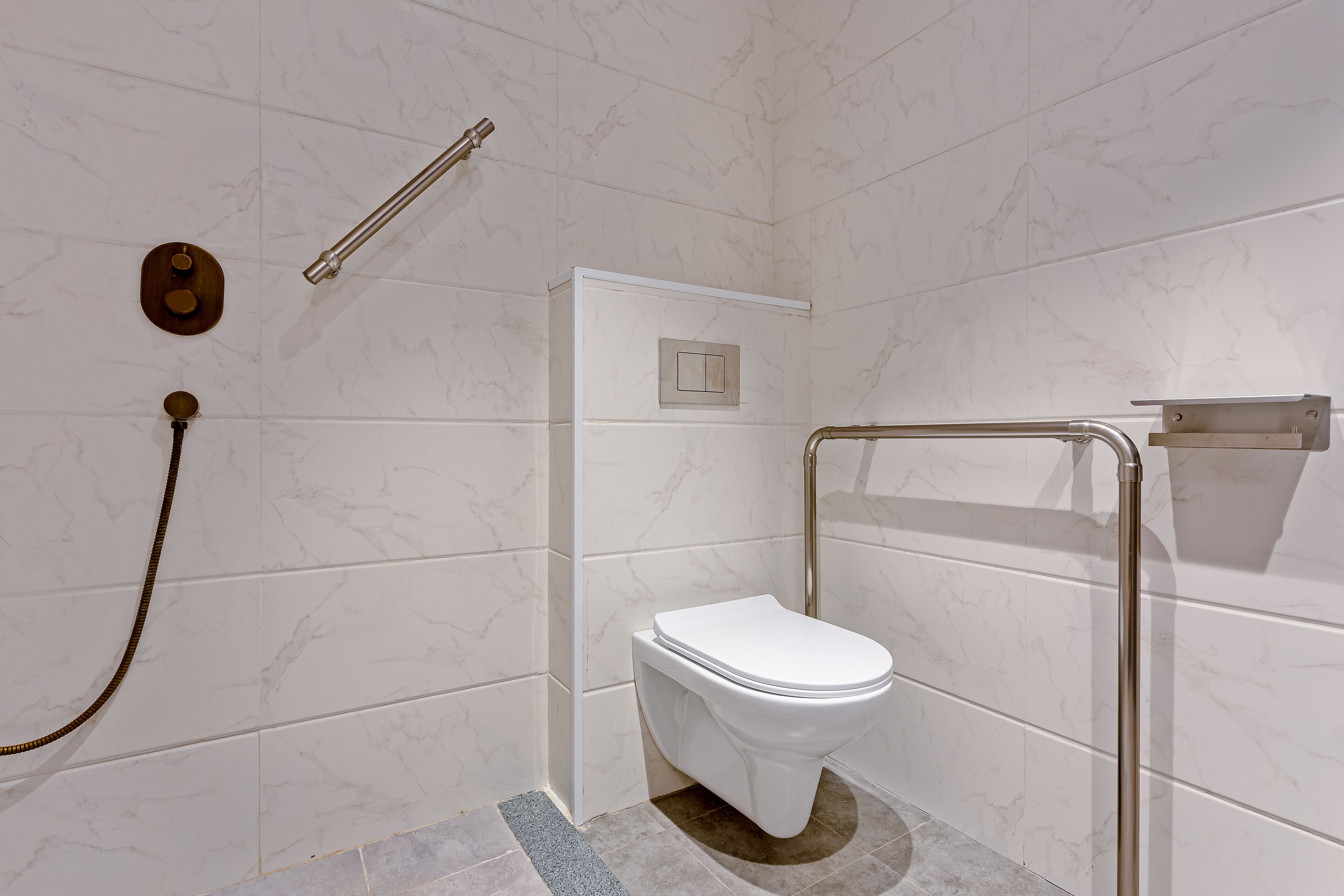 A modern bathroom with a white toilet, a handheld showerhead, and a grab bar.