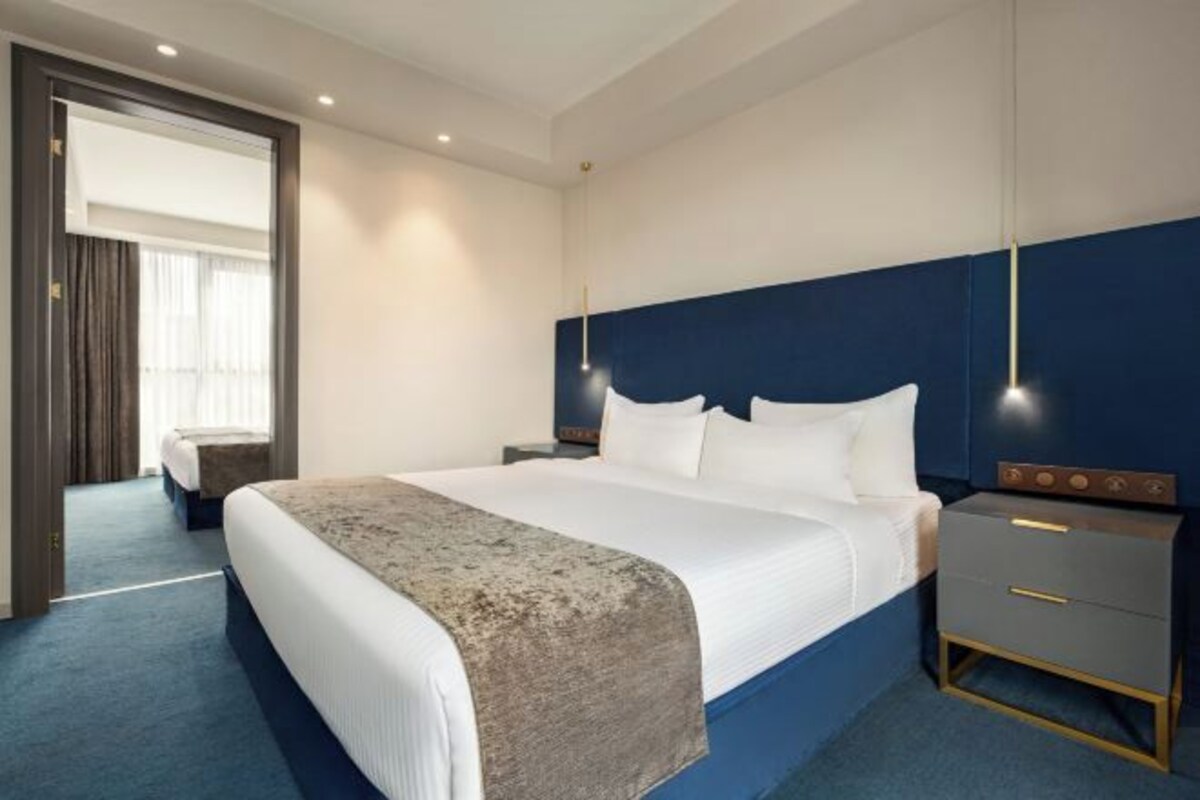 Une chambre d’hôtel moderne avec un grand lit, une table de chevet et une petite table d’appoint.