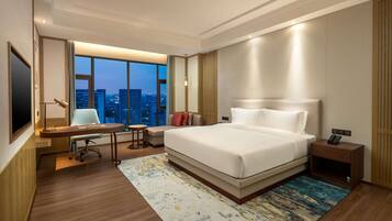 Un hotel moderno con una cama grande, un escritorio, una silla y vistas a la ciudad.