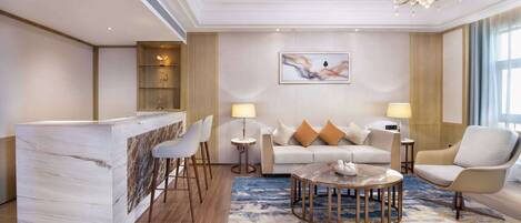 A modern hotel room with a marble bar, a round coffee table, and a sofa with cushions.