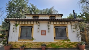 Un petit bâtiment à deux étages, doté d’un toit en tuiles, de deux fenêtres avec des barreaux en métal et d’une cheminée.