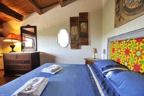 Ein Schlafzimmer mit Bett, Kommode, Spiegel und Wandbildern.