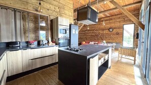 A rustic cabin-style kitchen with wooden beams, a central island, and modern appliances. - Grange de Marius - Authentic Savoyard barn (Albiez-Montrond)