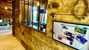 A wooden cabin interior with a large window, wooden walls, and a bulletin board with various papers and photos. - Grange de Marius - Authentic Savoyard barn (Albiez-Montrond)