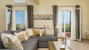 Ein Wohnzimmer mit grauem Sofa, einem Couchtisch und Blick ins Freie durch große Fenster.
