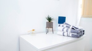 A white desk with a small potted plant, a bottle of perfume, and folded towels. - Large Shoreditch, Hoxton 3-bed Garden Flat (London)