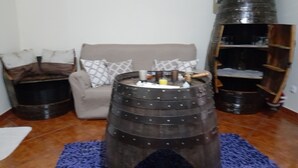 A living room with a round, barrel-shaped coffee table, a grey armchair, and a blue rug.