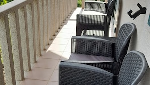 A balcony with wicker furniture and a view of mountains.