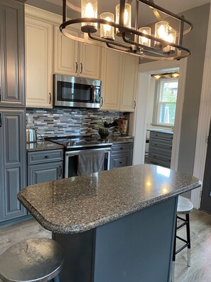 A modern kitchen with granite countertops, stainless steel appliances, and a central island.