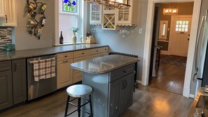 A kitchen with a central island, stainless steel appliances, and a wine rack on the wall.