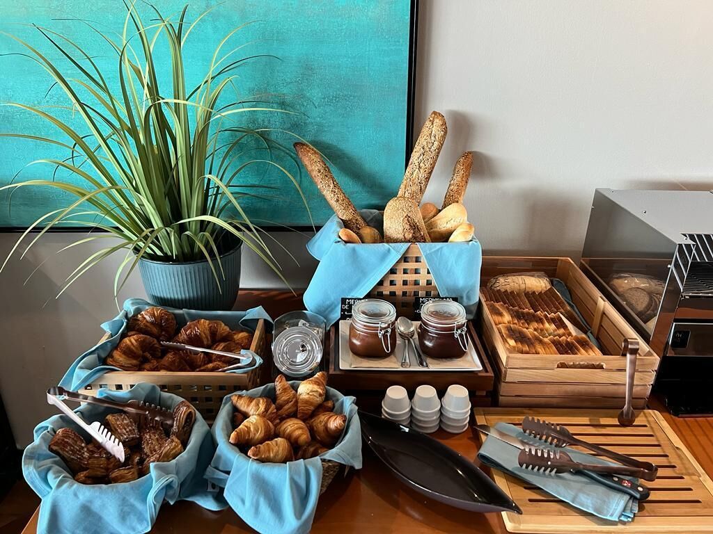 A breakfast buffet with croissants, bread, jams, and utensils.