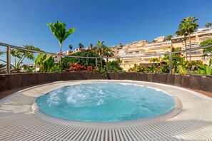 A hot tub surrounded by tropical plants and a view of a residential area with buildings. - Wyndham Residences Costa Adeje (Adeje)