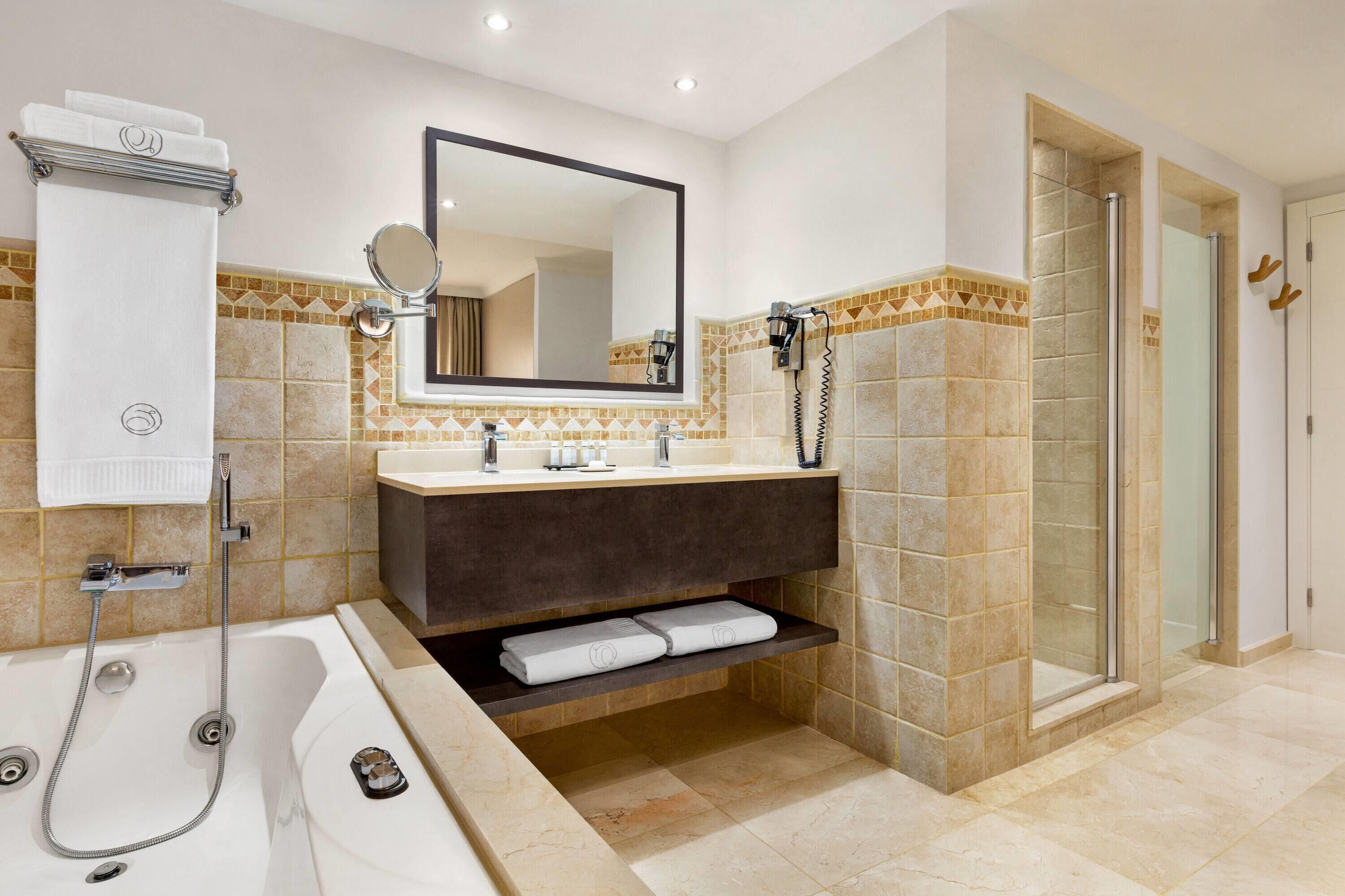 A modern bathroom with a bathtub, a large mirror, a vanity with a sink, and a shower area.