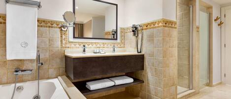 A modern bathroom with a bathtub, a large mirror, a vanity with a sink, and a shower area.