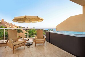 A balcony with wicker chairs, a small round table, and a large umbrella. - Wyndham Residences Costa Adeje (Adeje)