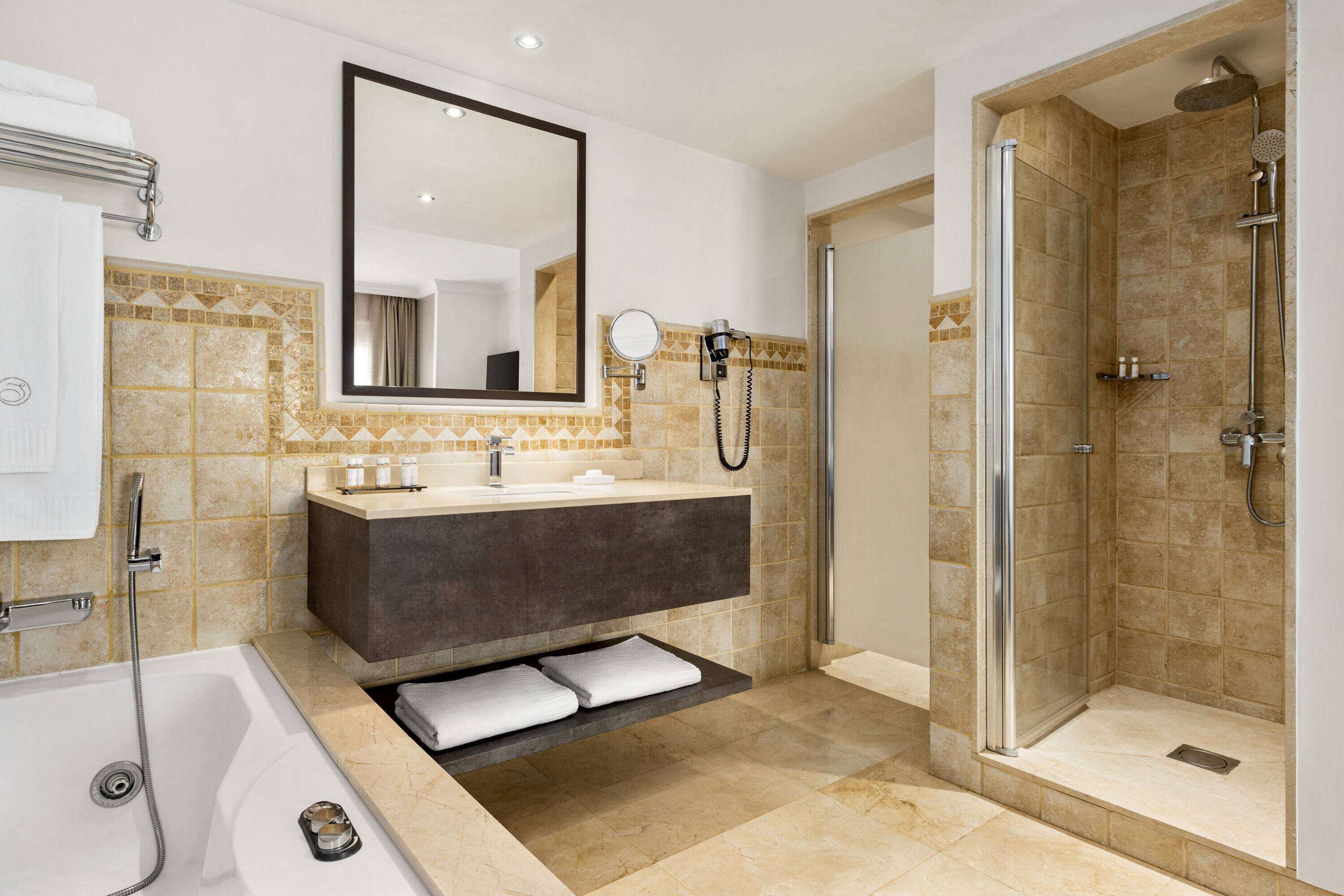 Ein modernes Badezimmer mit einer Badewanne, einem Waschtisch mit Spiegel und einer Duschkabine.