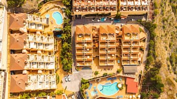 Un resort con varias piscinas, tumbonas y un patio central.