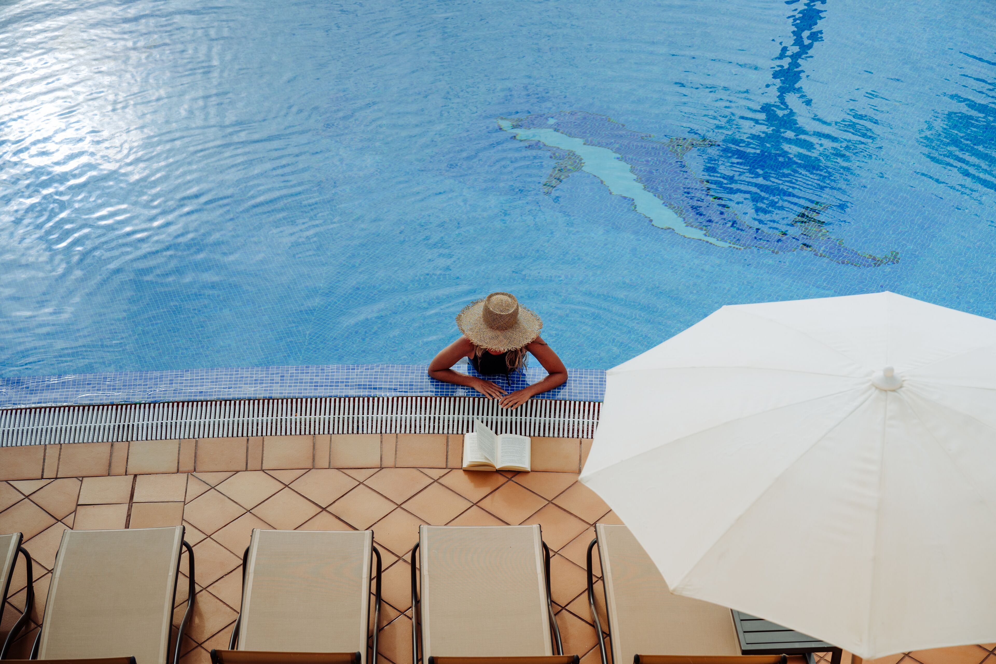 A pool area with lounge chairs and a large umbrella.