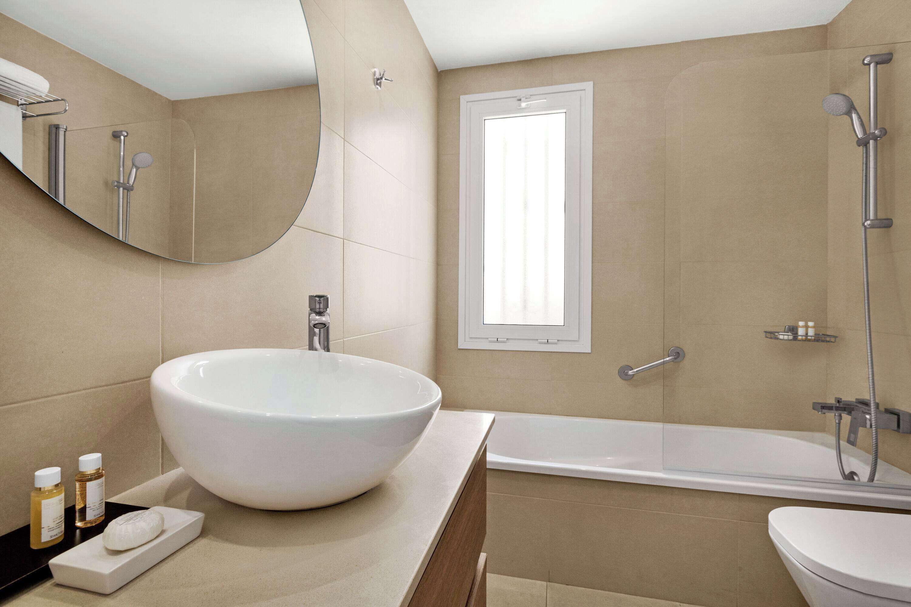 Un bagno moderno con un ampio lavandino bianco, una vasca e una doccia.