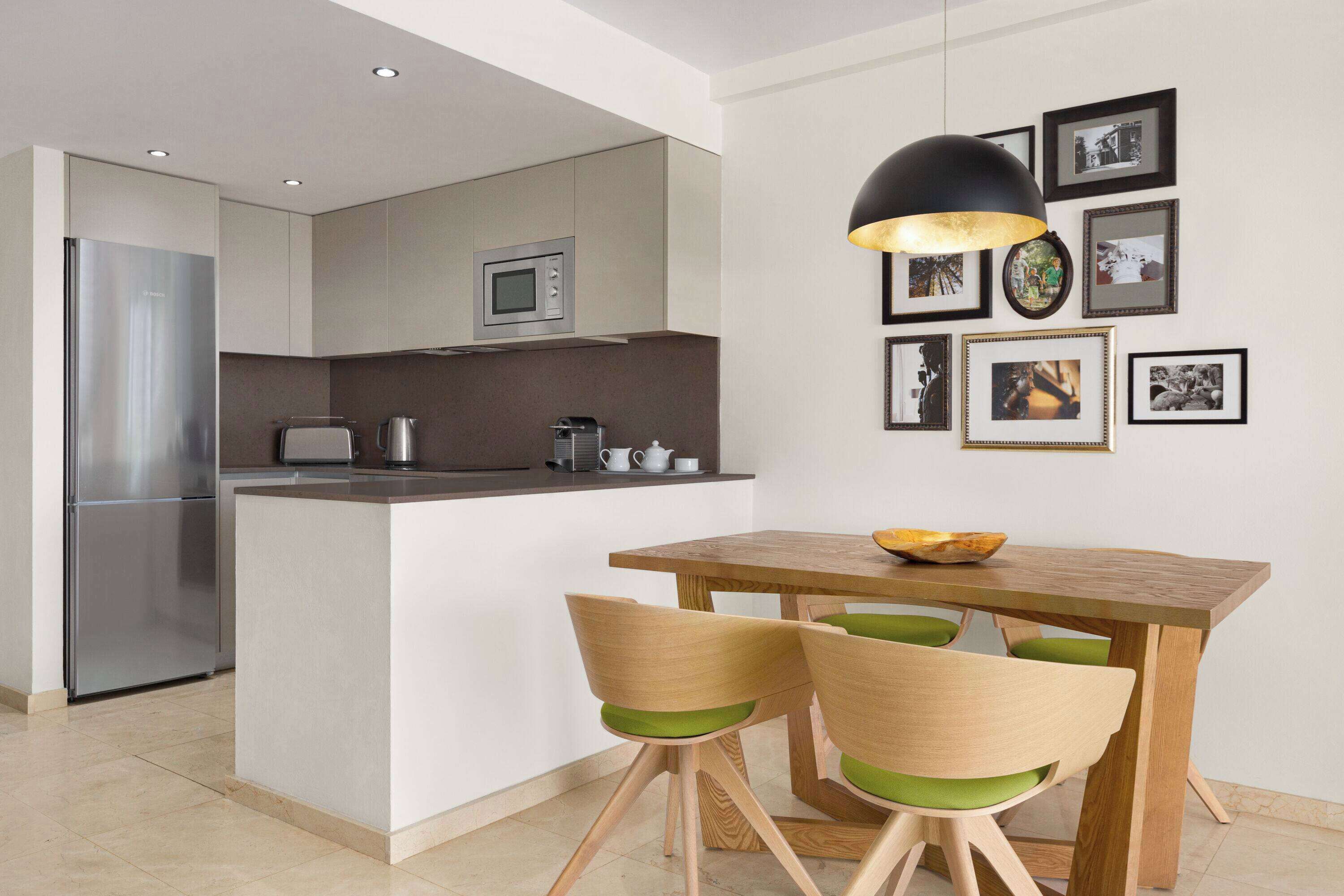 A modern kitchen with a central island, wooden chairs, and a dining table.