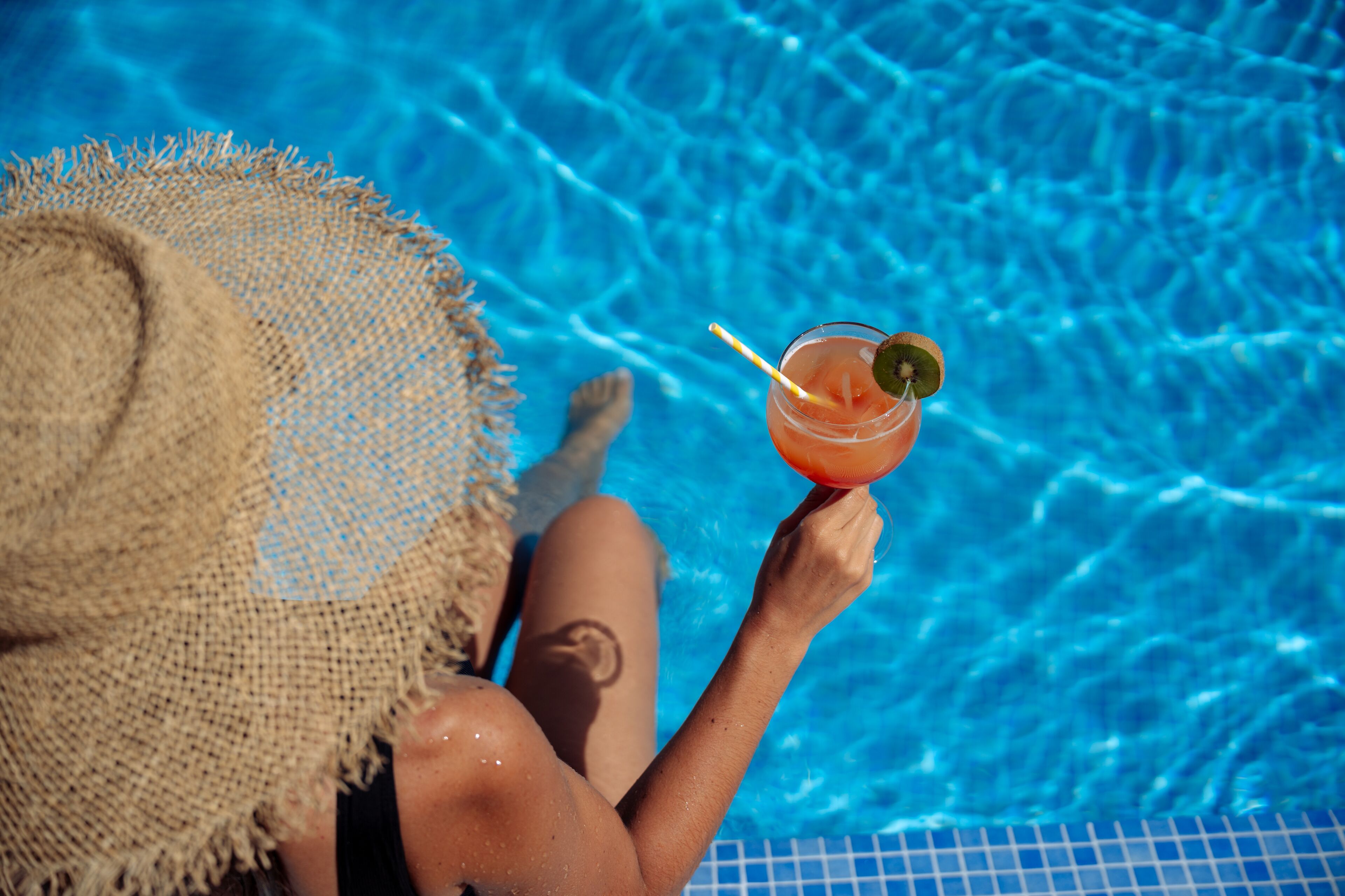 A person relaxing in a swimming pool with a drink.