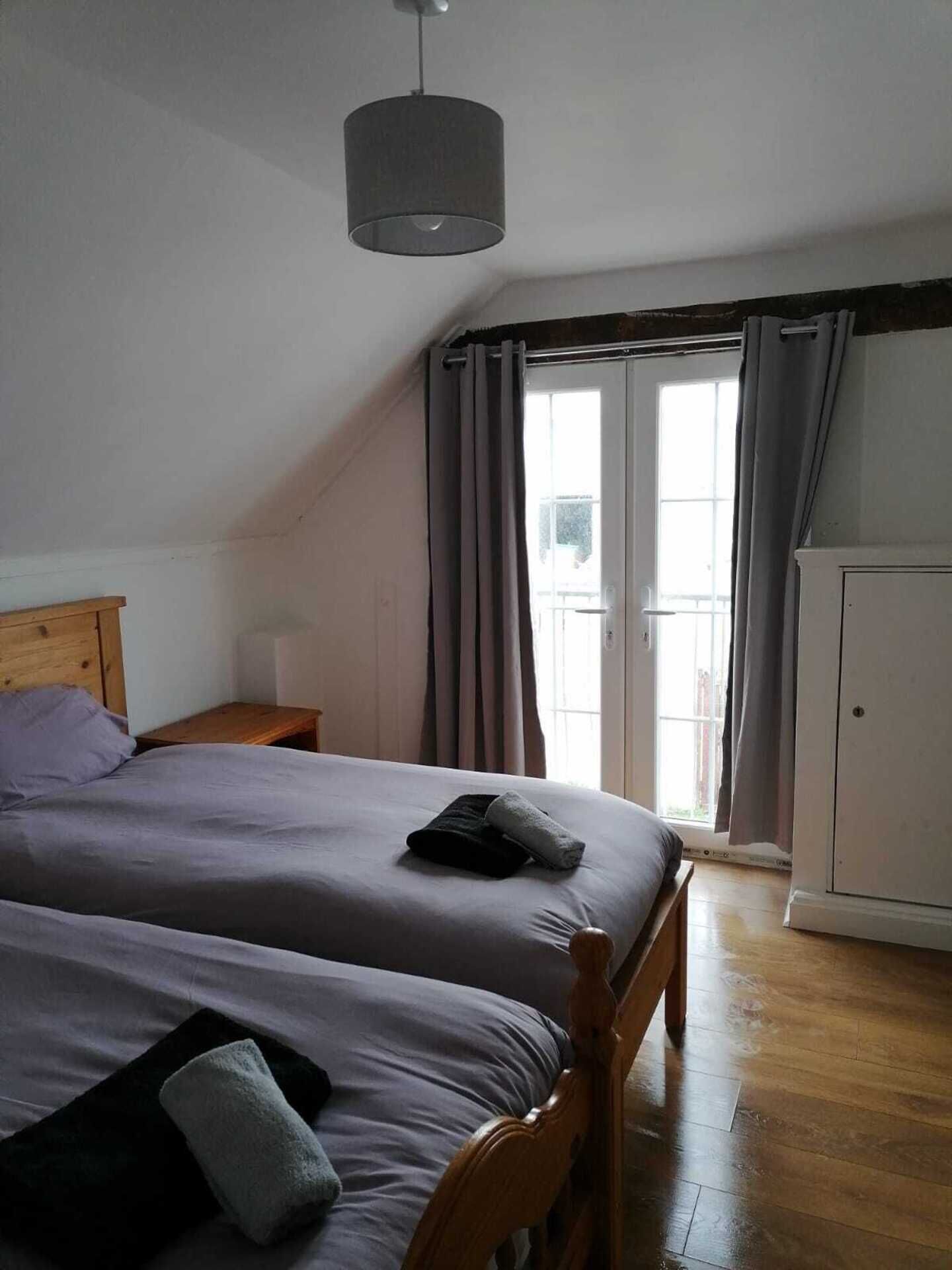Ein Schlafzimmer mit einem Bett, einem Nachttisch, einem Kleiderschrank und einem Fenster mit Vorhängen.