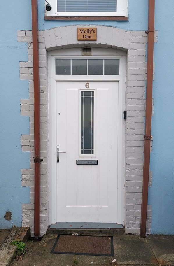 A white door with the number 6, a nameplate reading "Molly's Den," and a small window above the door. - Nice big 2 Double Bedroom Apartment in the Town (Newquay)