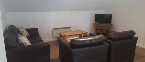 A living room with a sofa set, a coffee table, a television, and a pendant light.