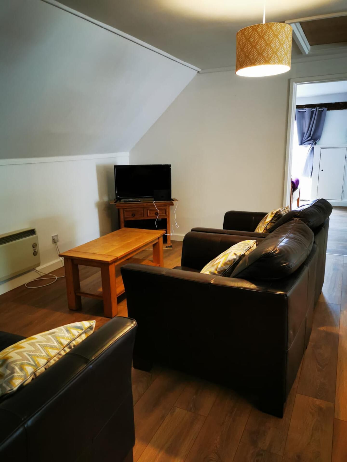A living room with a sofa, a wooden table, and a television on a stand.