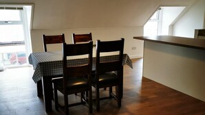 Ruokailutila, jossa on neljälle katettu pöytä, puiset tuolit ja riippuvalaisin.