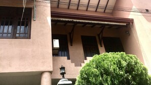 Un bâtiment à deux étages, doté d’un toit plat, d’un balcon et d’une clôture verte.
