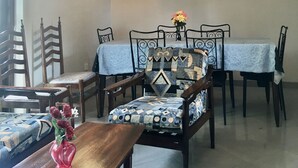 Un coin repas agrémenté d’un lustre, d’un ventilateur de plafond et d’une table dressée pour quatre personnes, avec des nappes et des chaises à motifs.