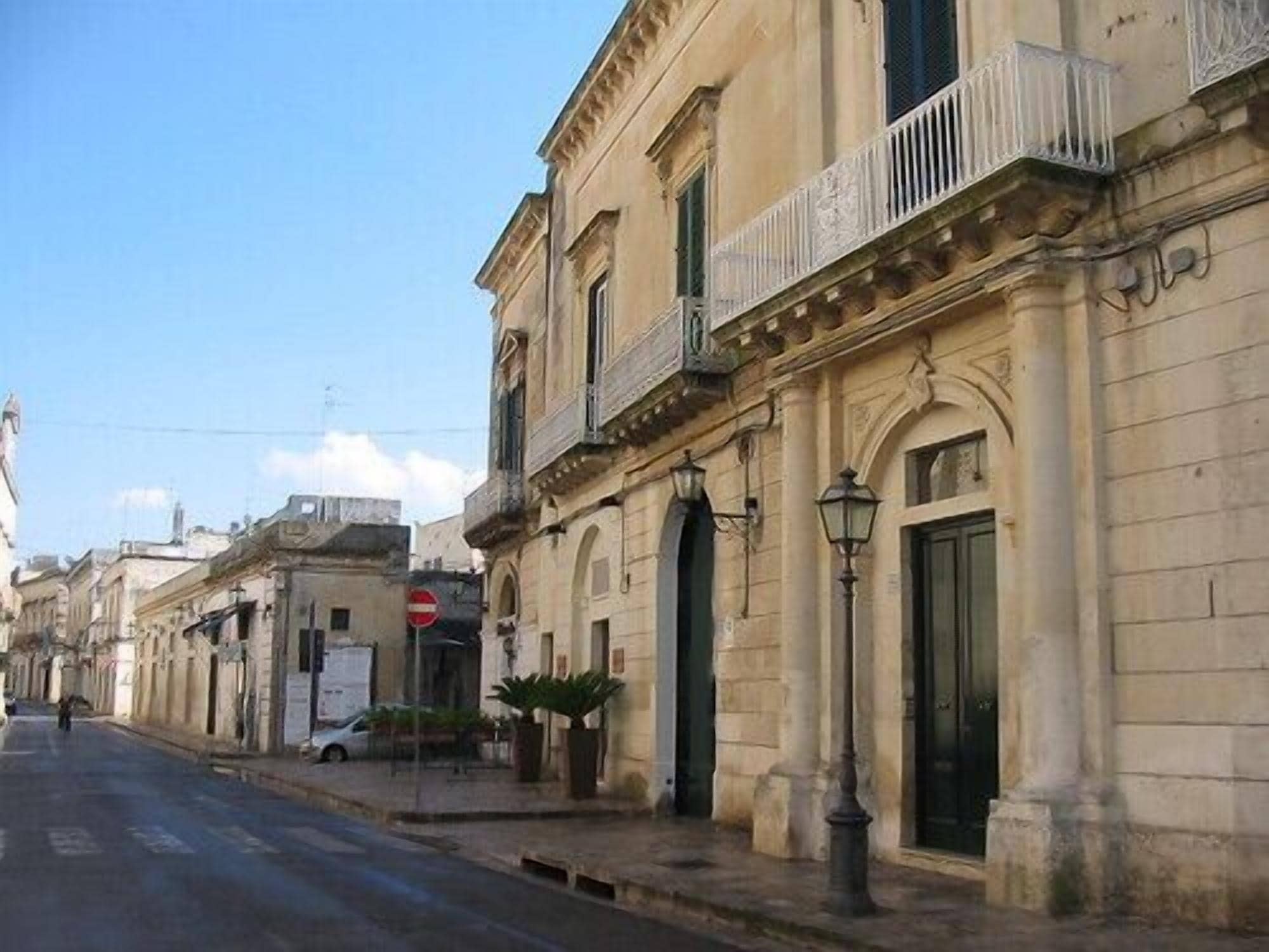 Une rue bordée de bâtiments historiques, un panneau indiquant l’interdiction de circuler et une voiture garée.