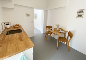 A modern kitchen with a wooden countertop, a sink, and a dining area with a wooden table and chairs.