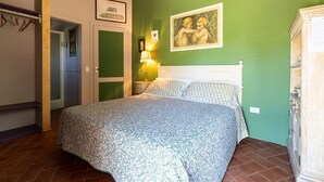 A bedroom with a bed, a nightstand, a lamp, and a green wall. - Intimate independent room for couples (Soriano Nel Cimino)