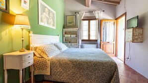 A bedroom with a bed, nightstand, lamp, and artwork on the walls. - Intimate independent room for couples (Soriano Nel Cimino)