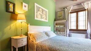 A bedroom with a bed, nightstand, lamp, and artwork on the walls. - Intimate independent room for couples (Soriano Nel Cimino)