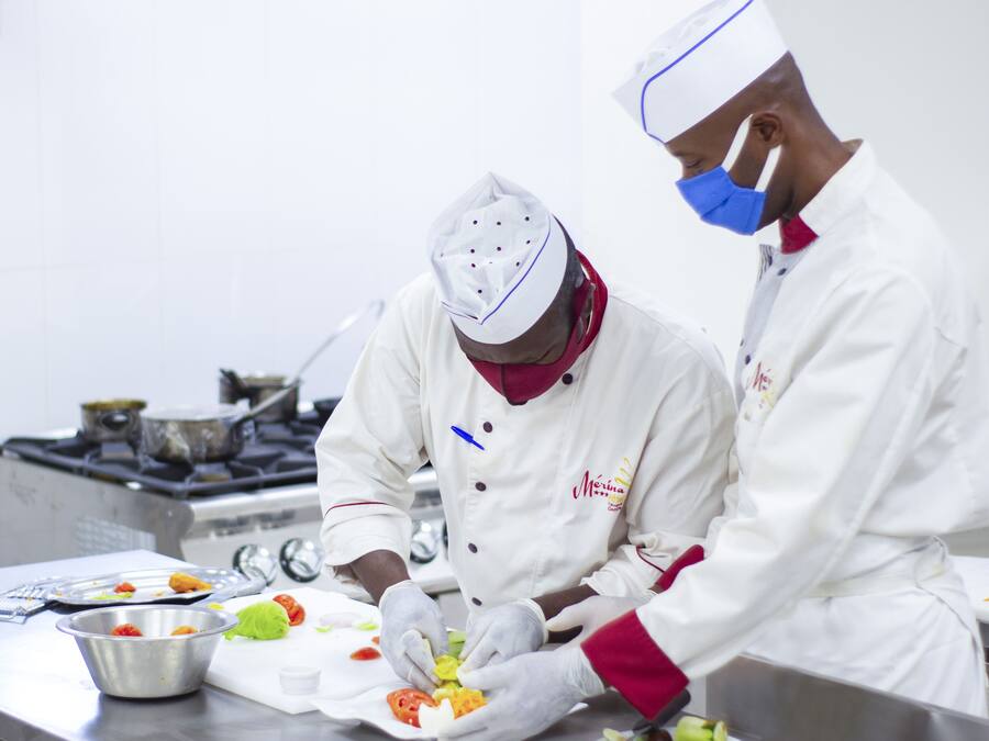 Two chefs preparing food in a professional kitchen.