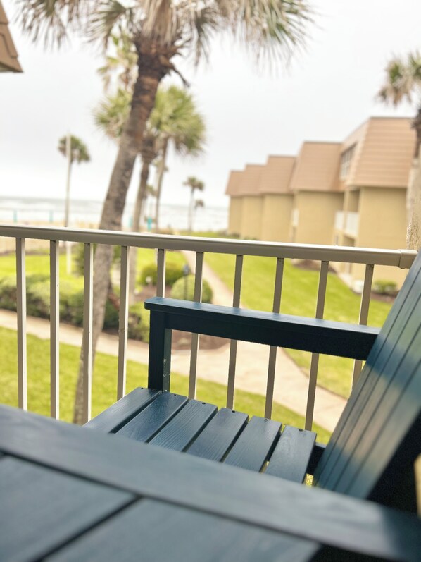 A balcony with a view of the ocean and palm trees.