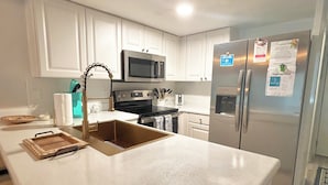 A modern kitchen with white cabinets, stainless steel appliances, and a large island with a sink.