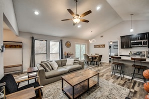 A spacious living room with a sofa, coffee table, and a dining area with chairs and a table. - JD's Getaway / Near DFW Airport (Lewisville)
