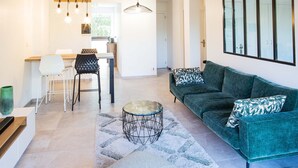 Una sala de estar moderna con un sofá verde, una mesa redonda y un comedor con mesa y sillas.