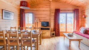 Un intérieur de chalet chaleureux avec un coin repas, un téléviseur et un canapé.